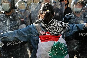 Masked riot police are confronted by one of many protesters who broke lockdown to protest deteriorating living conditions in Beirut, Lebanon, Tuesday, April 28, 2020 -Copyright AP Photo/Hussein Malla