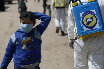 An internally displaced Syrian girl wears a face mask as members of the Syrian Civil defence sanitize the Bab Al-Nour internally displaced persons camp, to prevent the spread of coronavirus disease (COVID-19) in Azaz, Syria March 26, 2020. © REUTERS/Khal